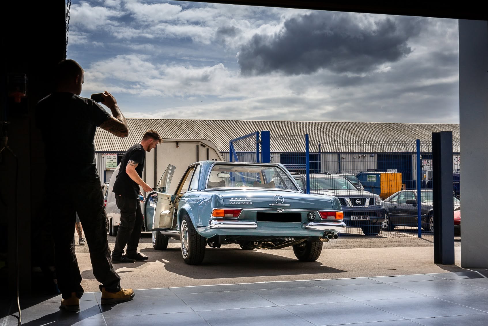 A restored classic Mercedes 280SL rolling out of the workshop