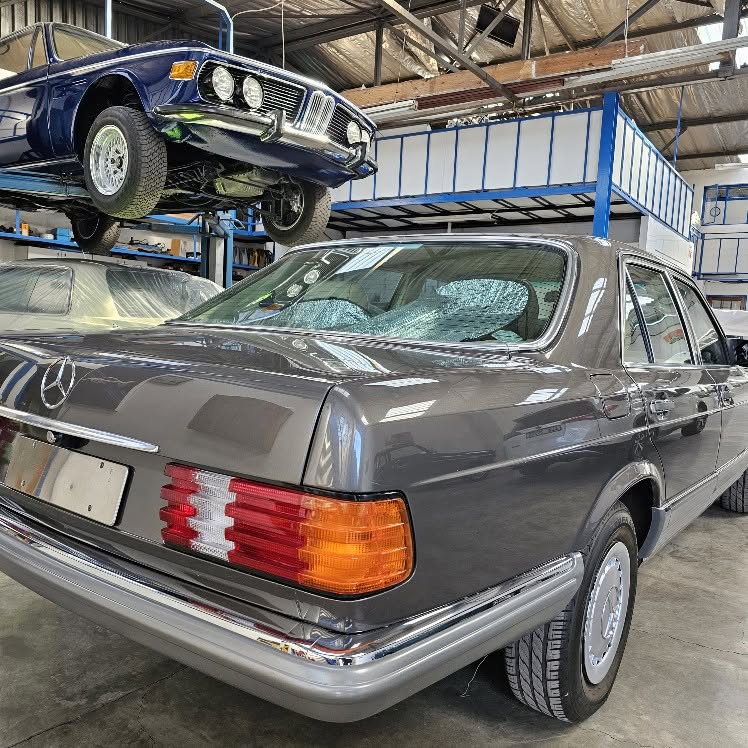 A classic Mercedes saloon and a BMW up on the lift in the AB Panelbeaters workshop